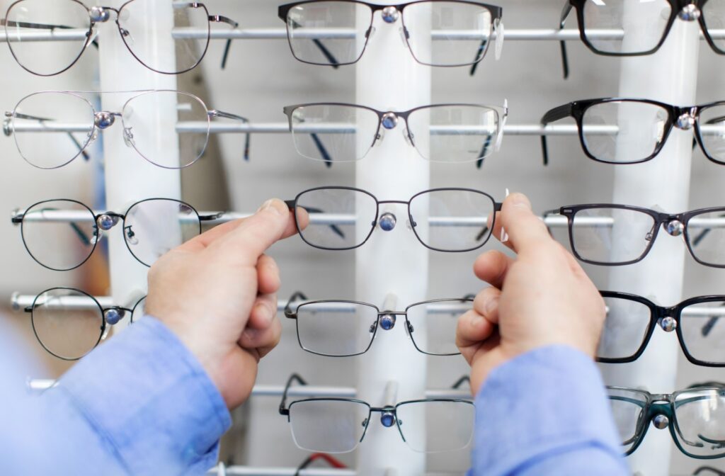 Person selecting eyeglass frames from a display rack in an optical store