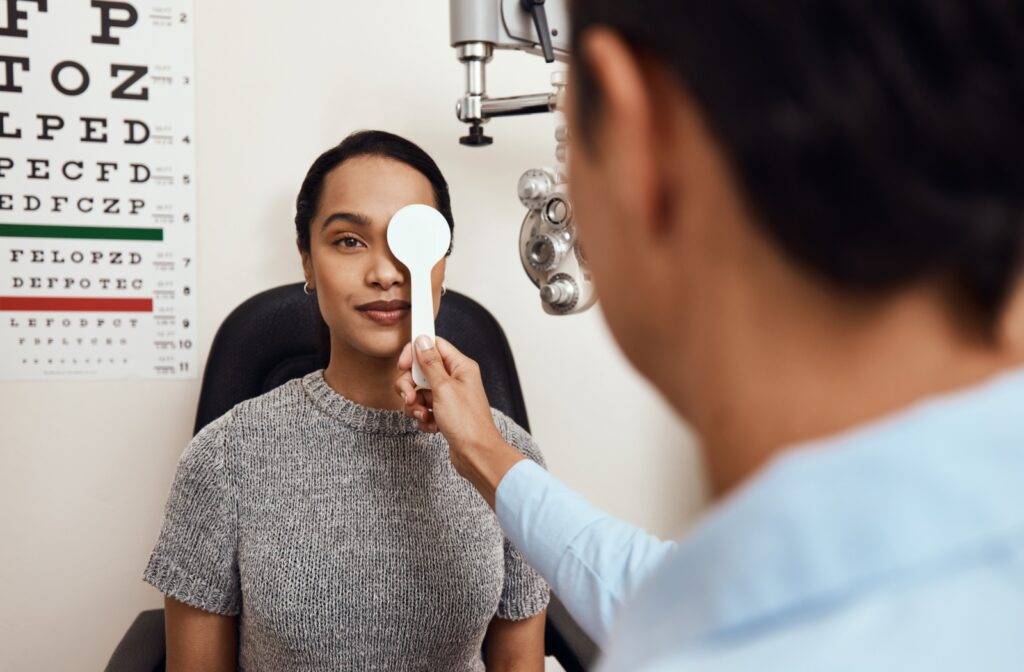 An eye doctor covers a patient's right eye to assess their visual sharpness during a routine eye exam.