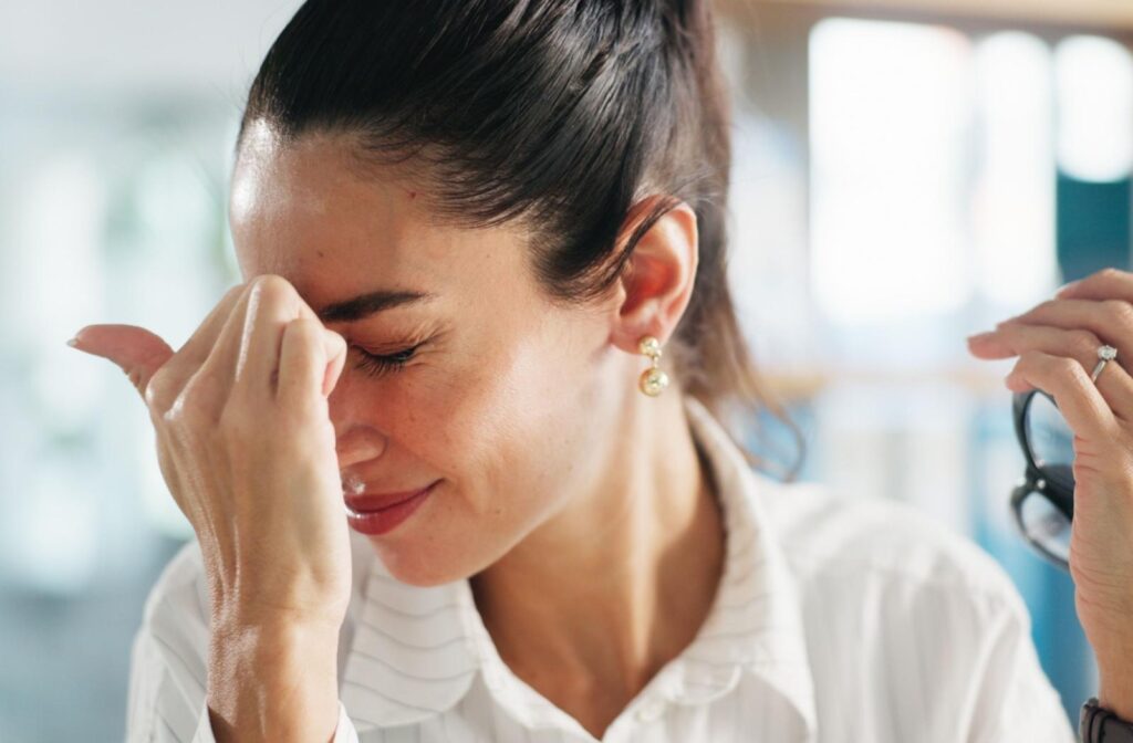 A person holding their hand up to their face, experiencing pain behind the eyes.
