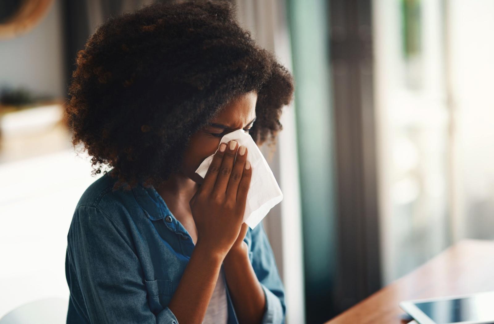 A person with a cold blowing their nose.